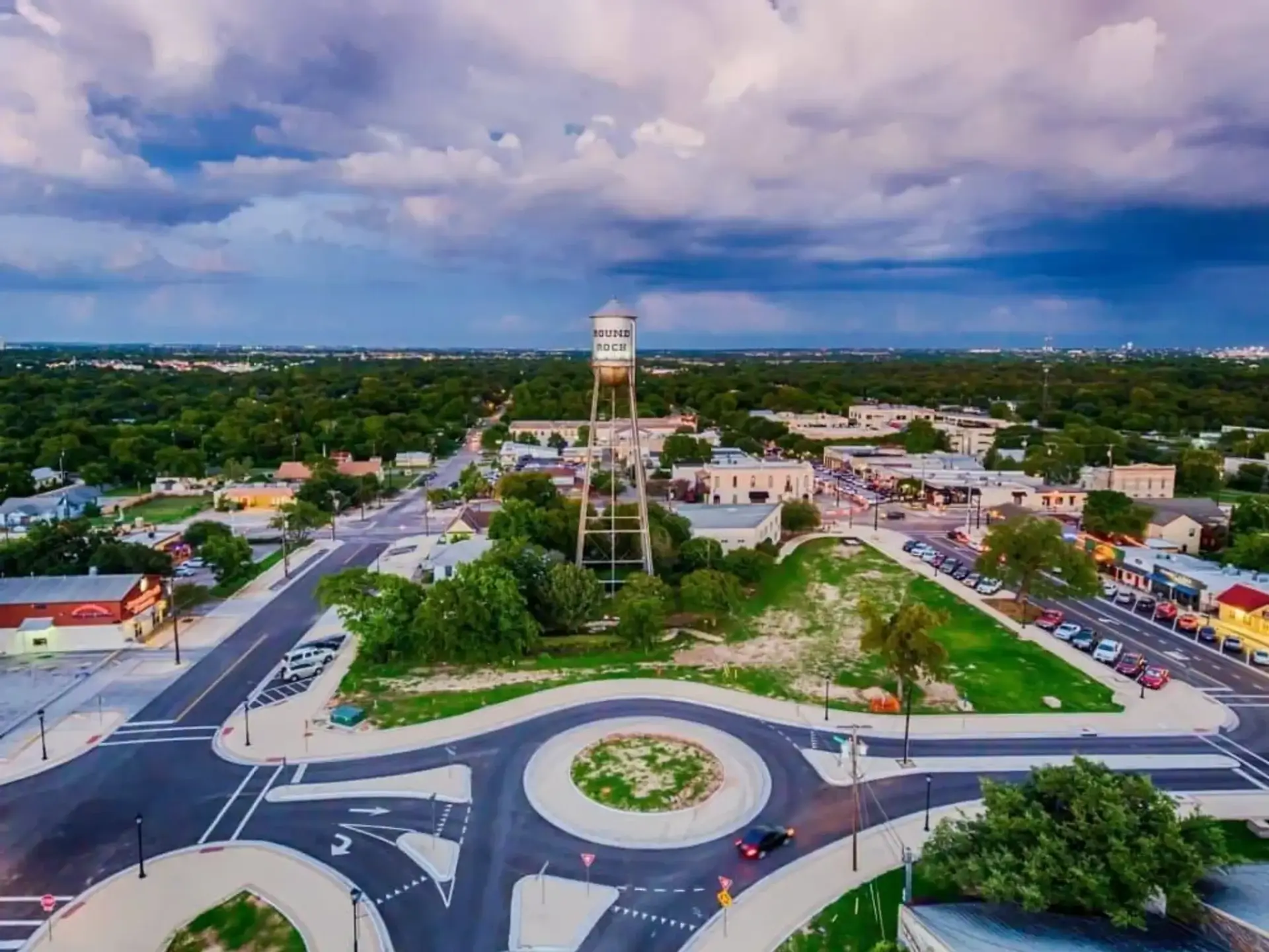 Aerial view of a roundabout with a water tower in a small town.